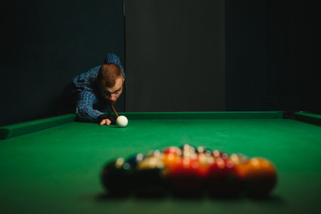 Young handsome man leaning over the table while playing snooker