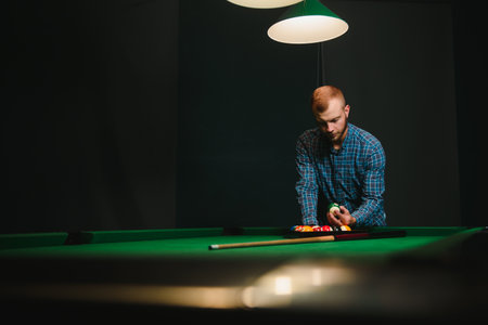 Young man playing billiards in the dark billiard clubの写真素材