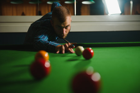 Young handsome man leaning over the table while playing snooker