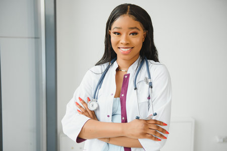 Closeup headshot portrait of friendly, smiling confident female healthcare professional with lab coat, arms crossed holding glasses. Isolated hospital clinic background. Time for an office visitの写真素材