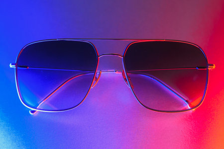 Stylish sunglasses shot using pink and blue abstract colored lighting with copy space.の写真素材