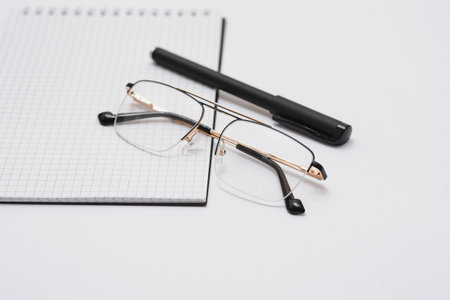 Blank diary, pen, and glasses on white background