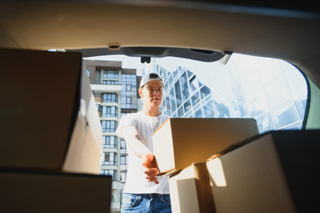 Delivery man picking up box from car.