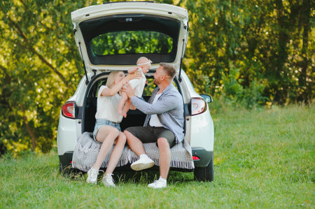 Happy family near car trunk on sunny day. road tripの写真素材