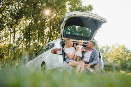 Family with kid sitting in car trunkの写真素材