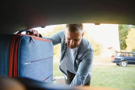 man putting bags in car trunk. ready for car travel. sunny morning
