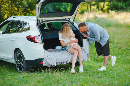 Happy family near car trunk on sunny day. road tripの写真素材