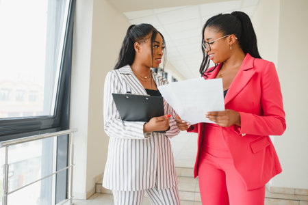 Two Businesswomen Shaking Hands In Lobby Of Modern Office