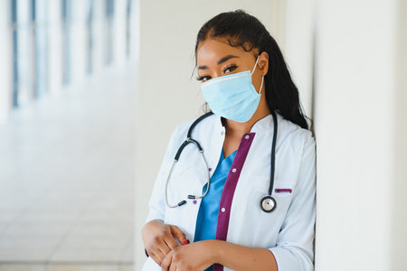 medicine, profession and healthcare concept - african american female doctor or scientist in protective facial mask in clinicの写真素材
