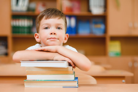 education and school concept - smiling little boy with many books at schoolの写真素材