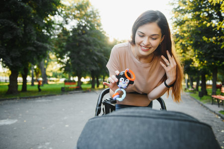 beautiful and young woman mother and baby in a stroller walking in the parkの写真素材