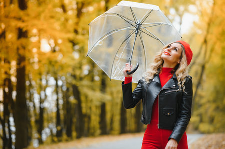 Beautiful girl with umbrella at autumn park.の写真素材