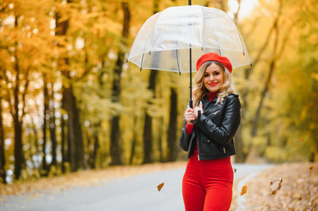 Beautiful girl with umbrella at autumn park.の写真素材