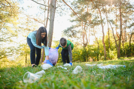 Woman volunteer and little boy picking up the plastic garbageの写真素材