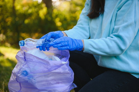 hand puts plastic debris in the garbage bag in the parkの写真素材