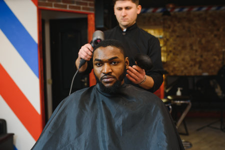 Close up of process of trimming of hair in barber shop. Qualified barber keeping clipper in hands...