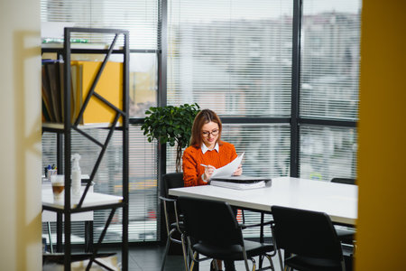 Portrait of a happy casual businesswoman in sweater sitting at her workplace in office