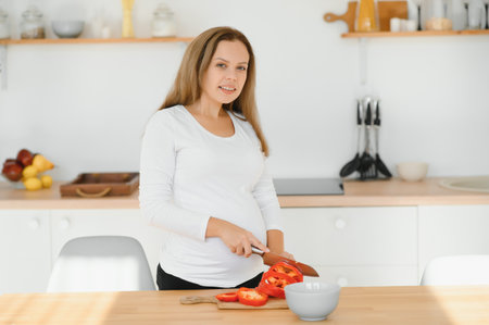 Pregnant woman in kitchen making saladの写真素材