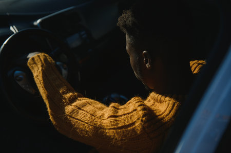 Handsome young African American man in his new high-tech electric vehicle while drinking. self driving vehicle conceptの写真素材