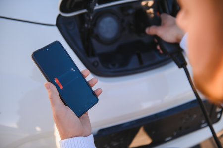 Smartphone app shows charging status of the electric car battery. Electro transport concept