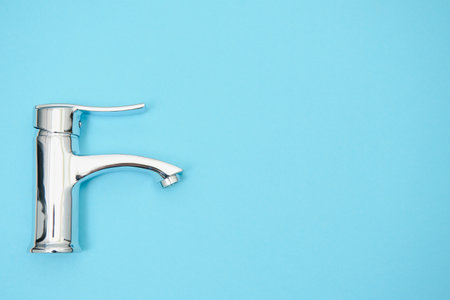 Single handle water tap on light blue background. New chrome or steel mixer tap .の写真素材