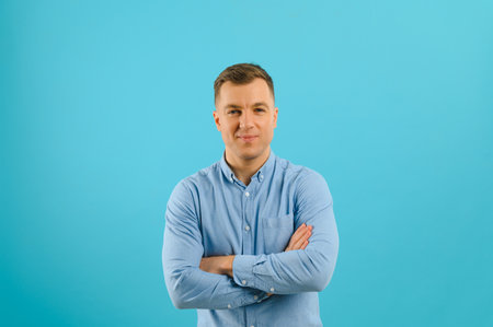 Happy smiling handsome man in clothing, showing copy space, visual imaginary or something, or pressing virtual button, aqua marine blue color background.の写真素材