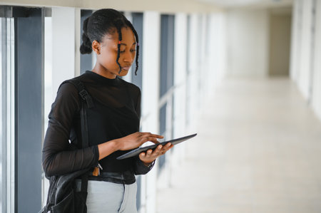 Happy smiling african-american student girl with backpack at university background. Technology, education, leisure conceptの写真素材