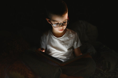 Child reading book in bed. Kids read at night. Little boy with fairy tale books in the bedroom....