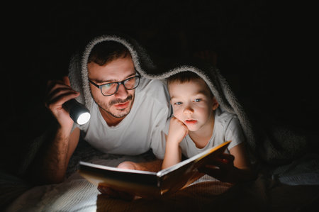 Father and his little son reading bedtime story at homeの写真素材