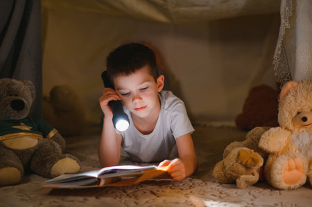 Two little child play at home in the evening to build a camping tent to read books with a flashlight and sleep inside. Concept of: game, magic, creativity, alarm systemsの写真素材