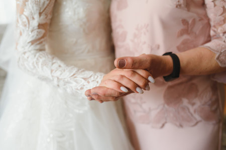 Bride on wedding day holding her mother's hands. Concept of relationship between moms and daughtersの写真素材