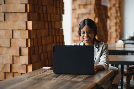 portrait of a smiling young african american woman sitting at cafe with laptopの写真素材