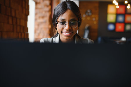 Focused young african american businesswoman or student looking at laptop, serious black woman working or studying with computer doing research or preparing for exam onlineの写真素材