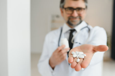 Senior male doctor with stethoscope in medical scrubs and holding bottle and tablets.の写真素材