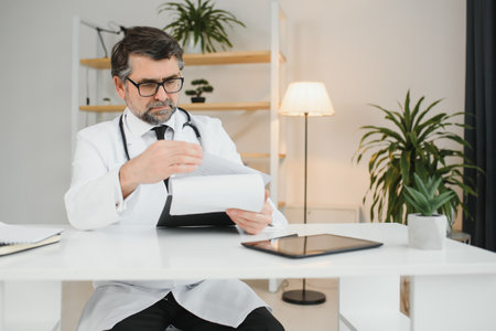 Portrait of senior doctor in white coat at workplace