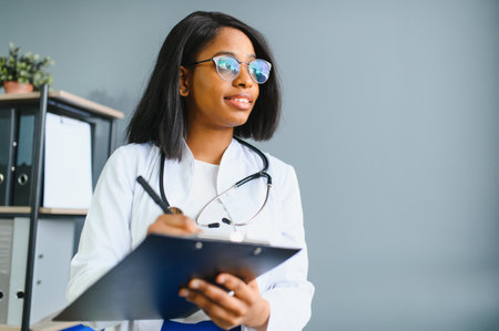 Portrait Of Smiling Female Doctor Wearing White Coat With Stethoscope In Hospital Officeの写真素材