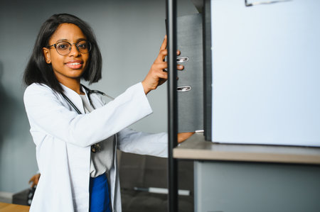 Smiling young adult indian female doctor wear white coat in medical clinic office. Happy beautiful health care india professional medic physician, therapist, headshot portrait.の写真素材