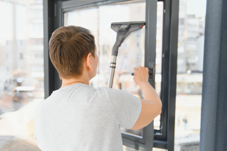 An attractive middle-aged woman is washing a window in a room.の写真素材