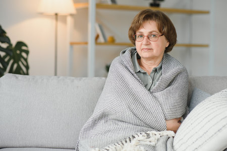 Relaxed grandmother sitting on the couch at homeの写真素材