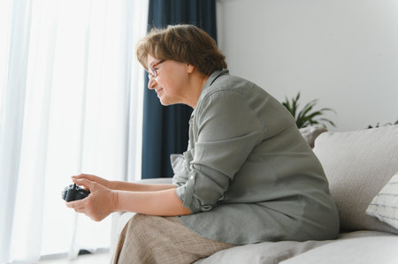 Older person having fun playing a console with a video game sitting on the sofa