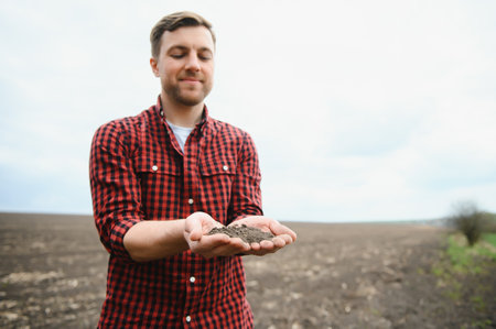 Farmer's hands hold a handful of fertile soil. The concept of agriculture, agribusiness. The gardener holds humus, fertilized soil, compost soil in his palms. Agriculture and fertilityの写真素材