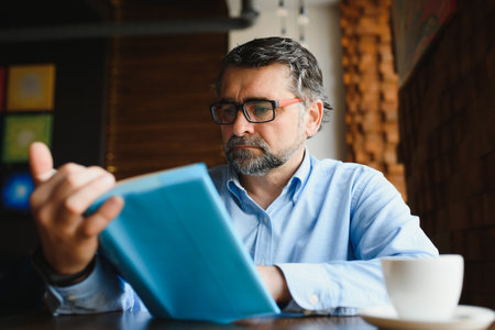 Mature handsome man reading a book in a cafe.の写真素材