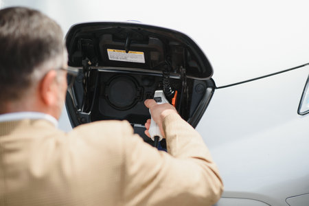 Man charges an electric car at the charging station.の写真素材