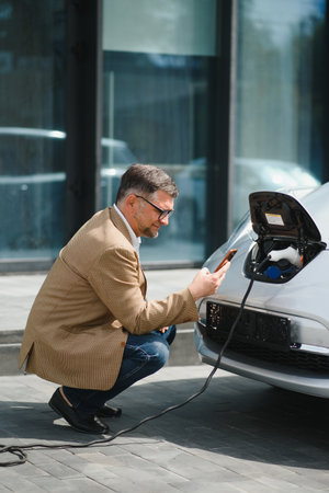 a businessman charges an electric car.の写真素材