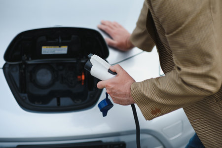 Man charges an electric car at the charging station.