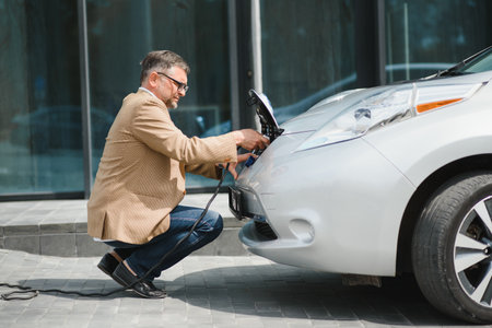 Man holding power connector for electric car.の写真素材