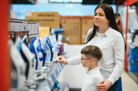 Woman with son choosing electric iron in electronics store.の写真素材