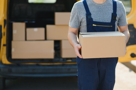 The courier brought the delivery of the box to the client. Courier service employee in uniformの写真素材