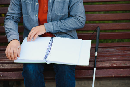 Blind man reading book on bench in park.の写真素材