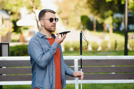 Young blinded man using phone and sending voice message.の写真素材